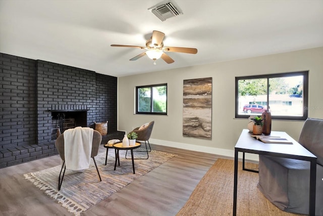 interior space with a wealth of natural light, a fireplace, ceiling fan, and light hardwood / wood-style floors