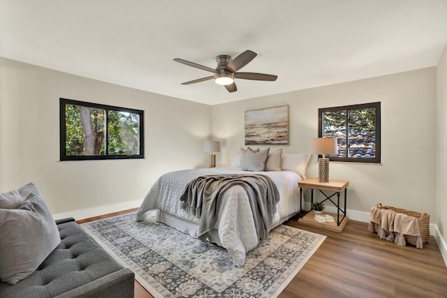 bedroom featuring hardwood / wood-style floors, ceiling fan, and multiple windows