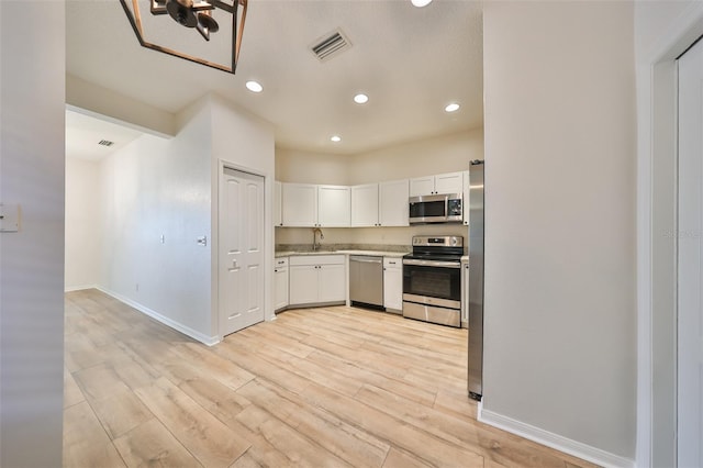 kitchen with white cabinets, light hardwood / wood-style floors, sink, and stainless steel appliances