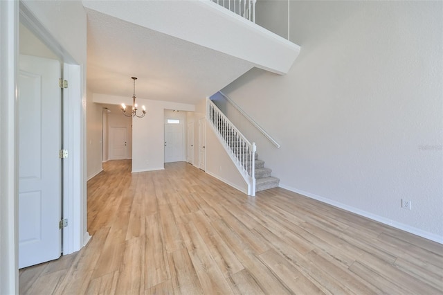 unfurnished living room with a chandelier and light hardwood / wood-style floors