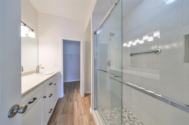 bathroom with hardwood / wood-style floors, vanity, and a shower with shower door