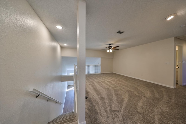 unfurnished living room with carpet flooring, a textured ceiling, and ceiling fan