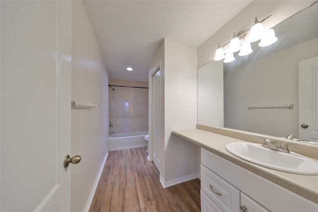 full bathroom with hardwood / wood-style floors, vanity, toilet, and tiled shower / bath