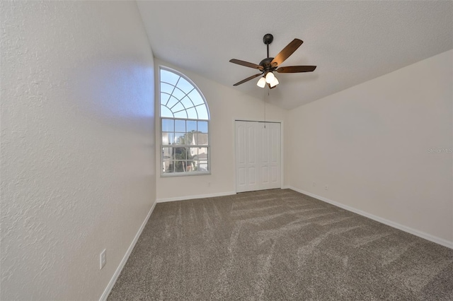 carpeted spare room featuring ceiling fan, lofted ceiling, and a textured ceiling