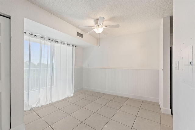 tiled spare room featuring a textured ceiling, electric panel, and ceiling fan