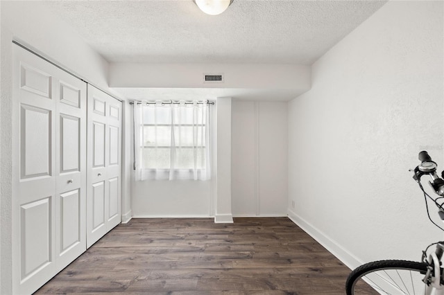 unfurnished bedroom featuring a closet, dark hardwood / wood-style flooring, and a textured ceiling