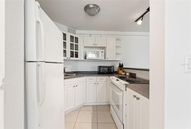 kitchen featuring white appliances, white cabinets, sink, a textured ceiling, and light tile patterned flooring