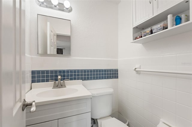 bathroom featuring vanity, toilet, and tile walls