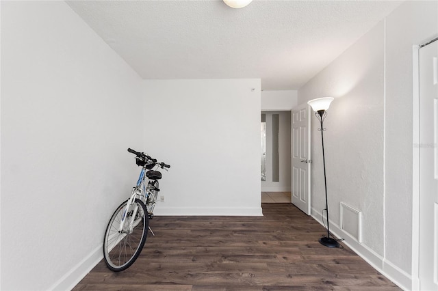 hallway featuring a textured ceiling and dark hardwood / wood-style flooring