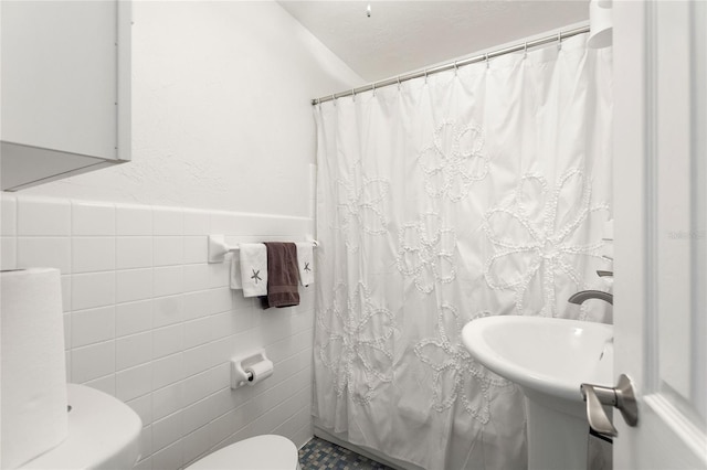 bathroom featuring a shower with shower curtain, tile walls, and toilet