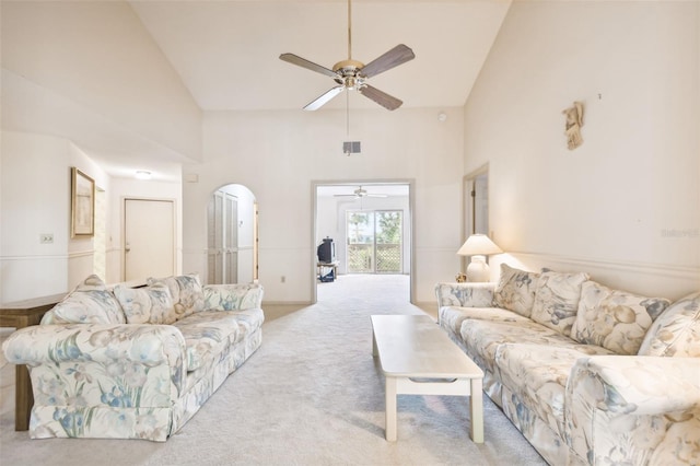 carpeted living room with ceiling fan and high vaulted ceiling