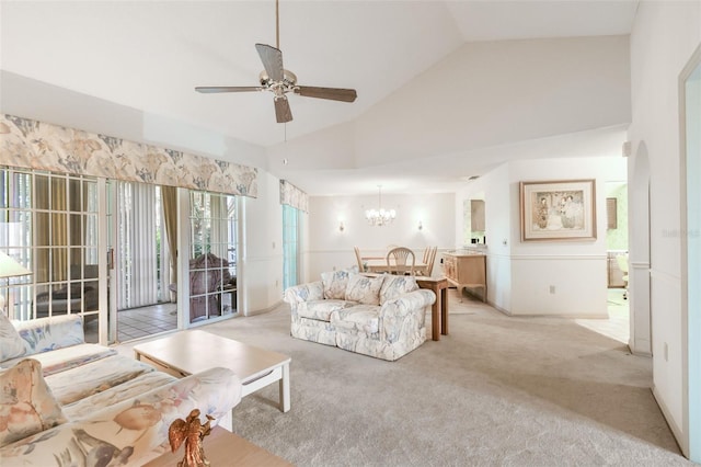 carpeted living room with ceiling fan with notable chandelier and high vaulted ceiling