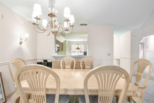 dining space with light colored carpet and an inviting chandelier