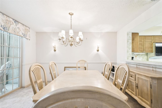 dining space with a textured ceiling, light colored carpet, and a notable chandelier