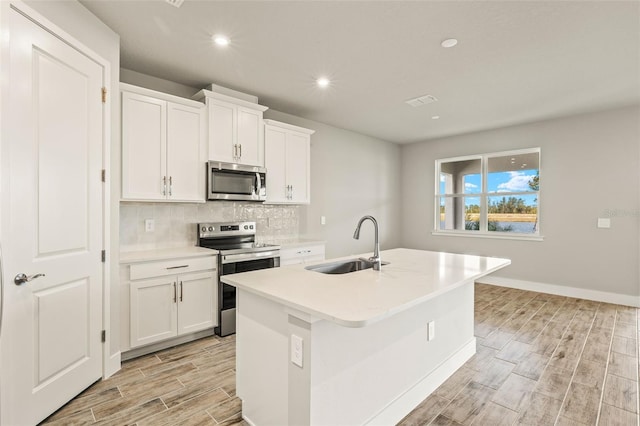 kitchen featuring a kitchen island with sink, sink, white cabinetry, and appliances with stainless steel finishes