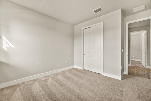 unfurnished bedroom featuring carpet flooring, a textured ceiling, and a closet