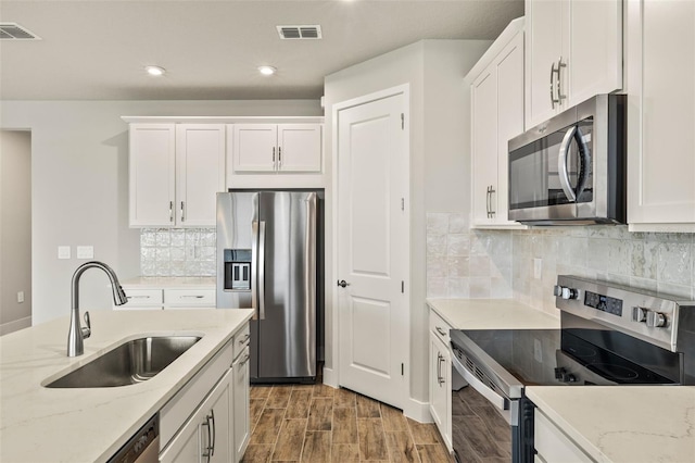 kitchen featuring white cabinetry, sink, light stone countertops, and appliances with stainless steel finishes