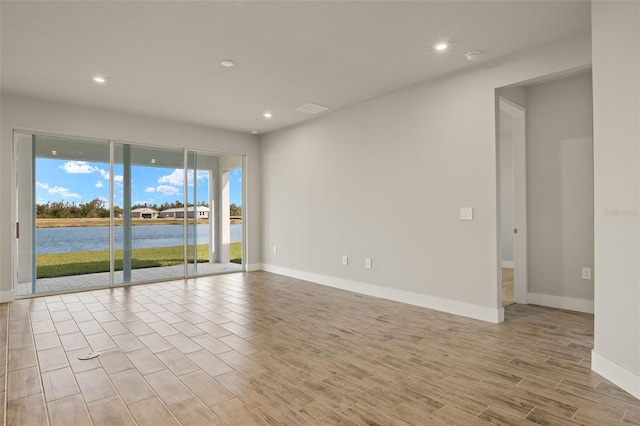 spare room with light hardwood / wood-style floors and a water view