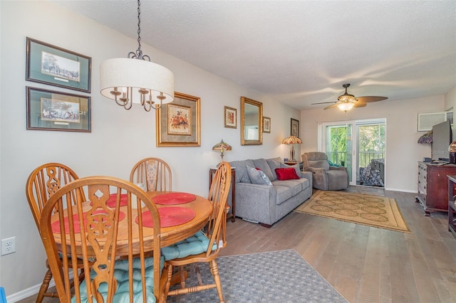 dining area featuring hardwood / wood-style flooring, ceiling fan with notable chandelier, and a textured ceiling