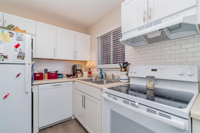 kitchen with white appliances, backsplash, white cabinetry, and sink