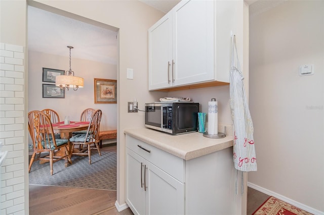 kitchen featuring light hardwood / wood-style floors, white cabinetry, and hanging light fixtures