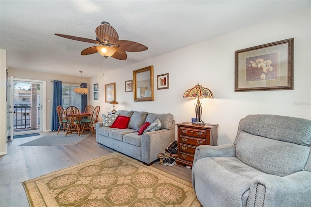 living room with ceiling fan, wood-type flooring, and a textured ceiling