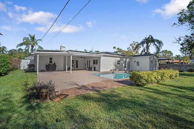 rear view of property featuring a lawn, ceiling fan, a patio area, and a fenced in pool