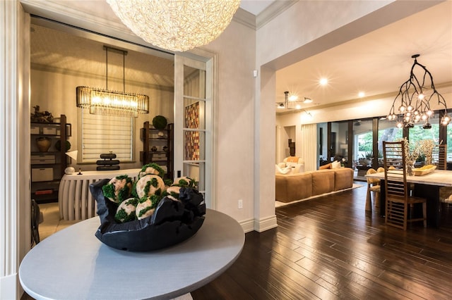 dining space with dark hardwood / wood-style flooring, crown molding, and a notable chandelier