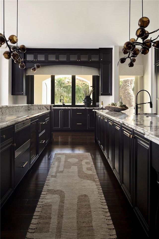 kitchen featuring decorative light fixtures, light stone counters, and dark wood-type flooring