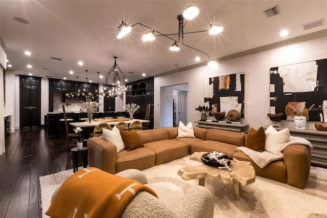 living room with ornamental molding, an inviting chandelier, and dark wood-type flooring