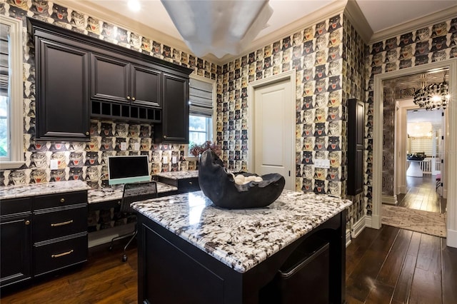 kitchen featuring a kitchen island, dark hardwood / wood-style flooring, ornamental molding, and light stone counters