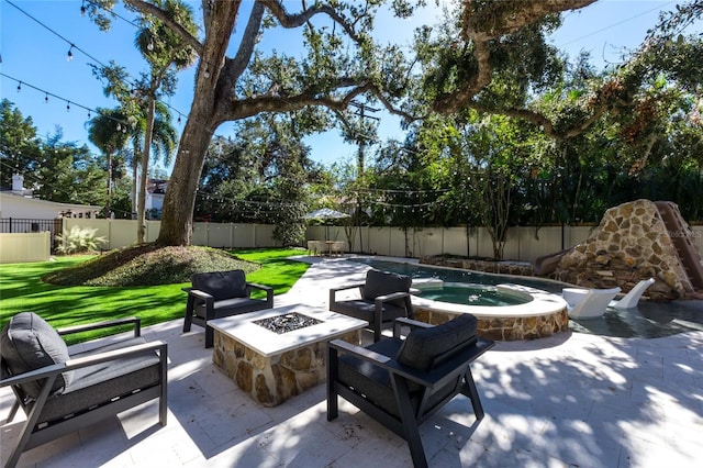 view of patio featuring an in ground hot tub and a fire pit