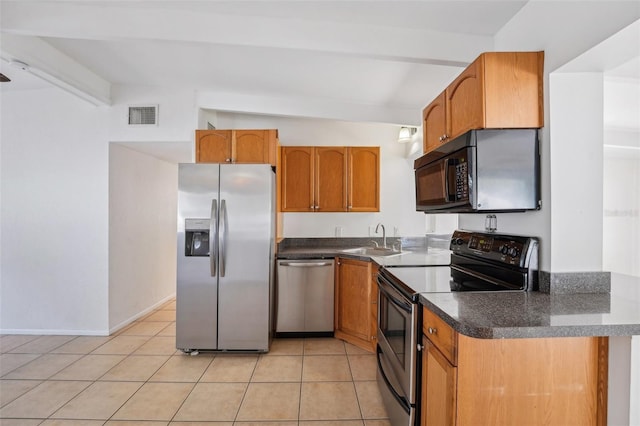 kitchen with light tile patterned flooring, vaulted ceiling with beams, stainless steel appliances, and sink