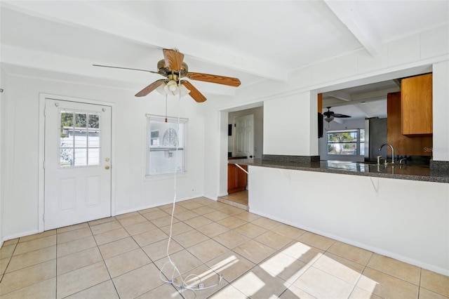 kitchen with beamed ceiling, kitchen peninsula, a wealth of natural light, and sink