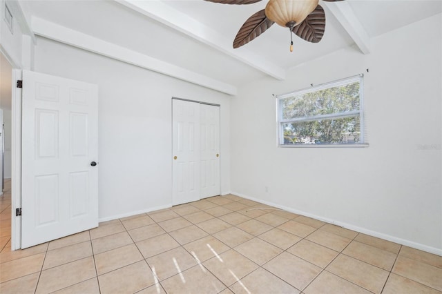 unfurnished bedroom with beam ceiling, ceiling fan, a closet, and light tile patterned floors