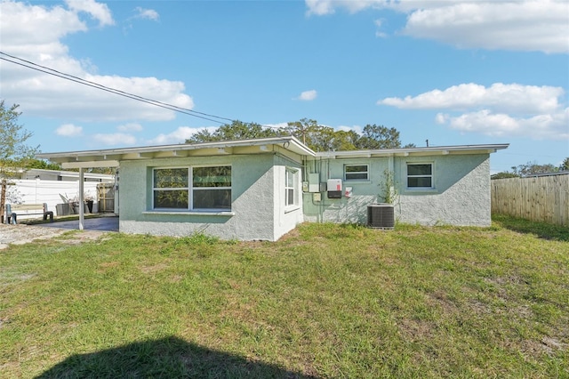 rear view of property with central AC and a yard