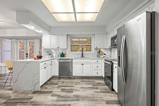 kitchen with a healthy amount of sunlight, sink, white cabinets, and stainless steel appliances