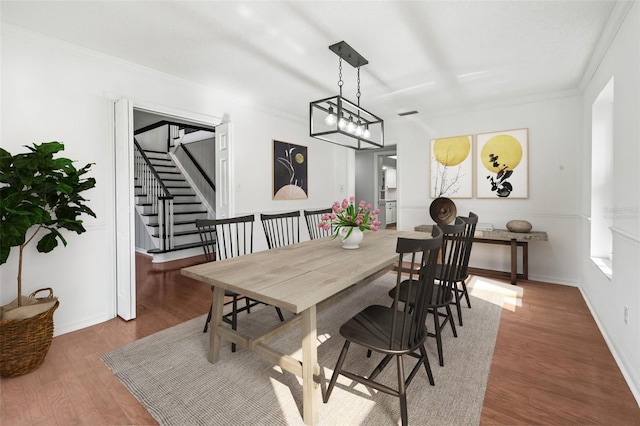 dining area with dark hardwood / wood-style flooring, crown molding, and an inviting chandelier