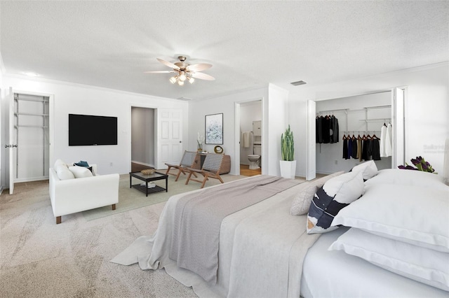 carpeted bedroom featuring ceiling fan, a textured ceiling, and ensuite bath