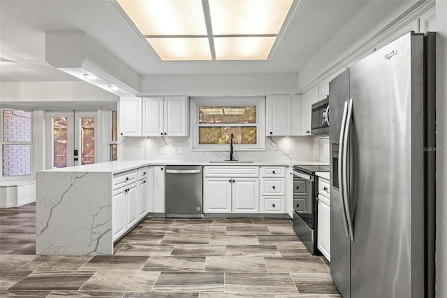 kitchen with backsplash, french doors, sink, white cabinetry, and stainless steel appliances