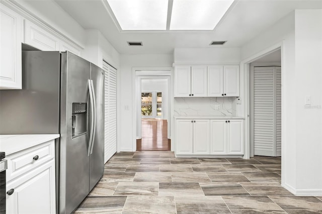 kitchen featuring stainless steel fridge with ice dispenser, backsplash, white cabinetry, and light wood-type flooring