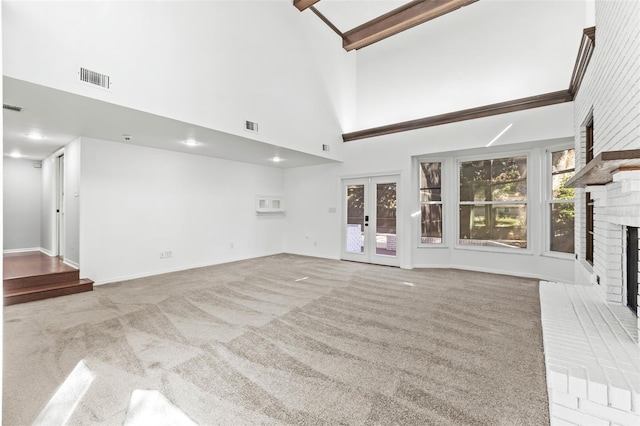 unfurnished living room featuring light carpet, a brick fireplace, high vaulted ceiling, and french doors