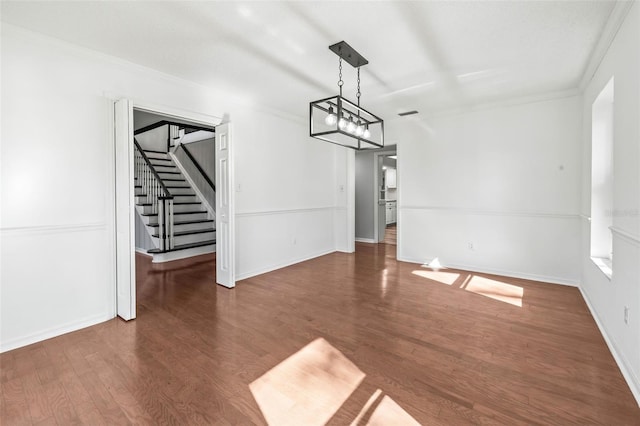 unfurnished dining area featuring a notable chandelier, dark hardwood / wood-style flooring, and crown molding