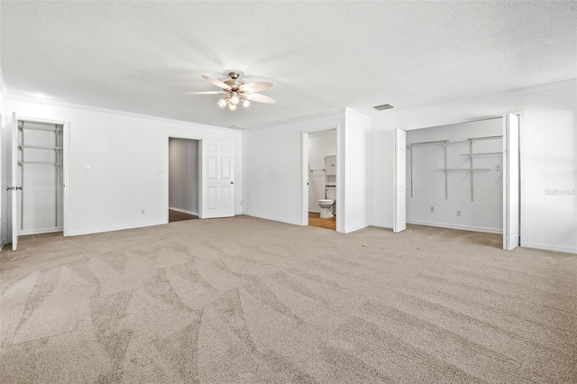 unfurnished bedroom featuring carpet flooring, ceiling fan, ensuite bathroom, and a textured ceiling