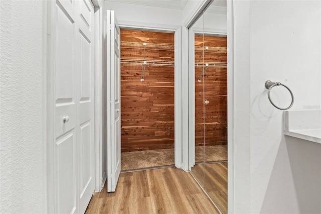 hallway with crown molding and light hardwood / wood-style flooring