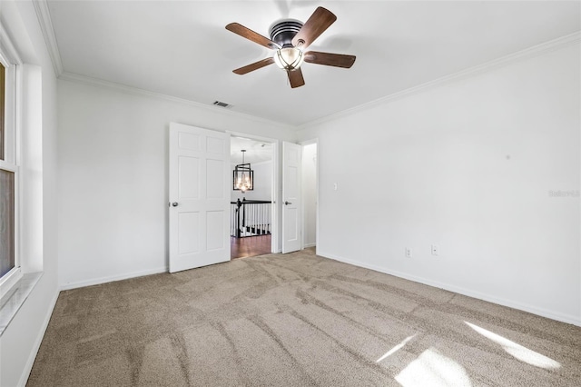 unfurnished bedroom featuring ceiling fan, carpet, and ornamental molding