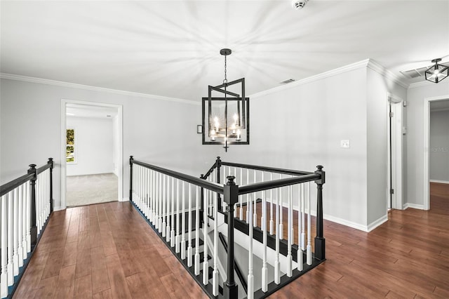 corridor with dark hardwood / wood-style flooring, ornamental molding, and an inviting chandelier