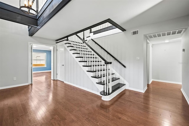 stairway with hardwood / wood-style flooring and a notable chandelier