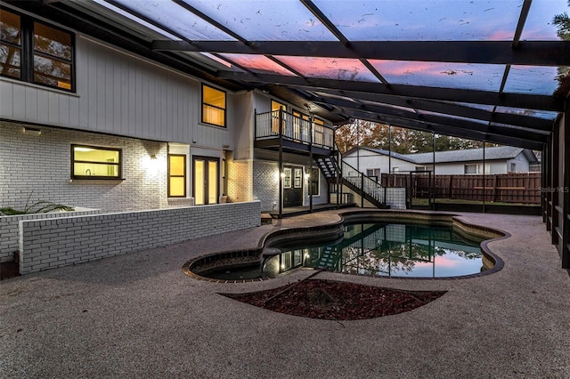 back house at dusk with a fenced in pool, a patio area, and a lanai