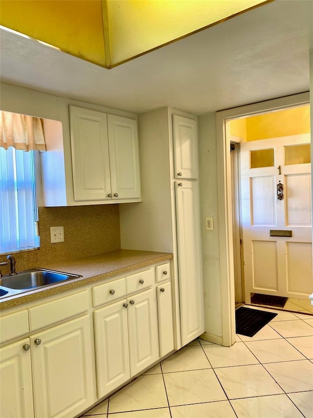 kitchen featuring backsplash, white cabinetry, and sink